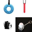 A collage featuring the "2 Chew Necklaces + 2 Fidget Toys Bundle" displays four unique sensory toys: a blue circular chew necklace with a star design, a red cylindrical pendant, a black and white twistable fidget toy, and a white paw-shaped keycap on a clear keychain. Each item is crafted to provide tactile stimulation.