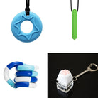 A collage of four fidget toy images from the 2 Chew Necklaces + 2 Fidget Toys Bundle: a blue star-shaped chewy necklace, a green cylindrical chewy pendant on a black string, a blue and white bendable fidget stick, and a white and pink paw keyboard fidget keychain on a silver ring.