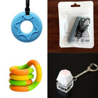 A collage featuring a blue star-cutout pendant, a green and orange twistable ring, a packaged fidget pendant, and a Paw Keyboard Fidget Keychain with a white cat paw button on a clear base showcases the "2 Chew Necklaces + 2 Fidget Toys Bundle (choose your colors).