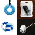 A collage of fidget toys from the 2 Chew Necklaces + 2 Fidget Toys Bundle: a blue and white folded bendy toy, a star-shaped chew necklace on a black string, a packaged silicone fidget toy with instructions, and a cat paw-shaped keychain clicker on a wooden surface.