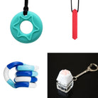 A collage of four sensory tools against a white background: a turquoise and green star-shaped chew necklace, a red gem-shaped chew necklace, a blue and white twisty fidget toy, and a keychain with a white paw-shaped tactile button atop a clear base from the "2 Chew Necklaces + 2 Fidget Toys Bundle (choose your colors).