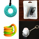 A grid of four sensory tools in the "2 Chew Necklaces + 2 Fidget Toys Bundle," featuring a teal star-shaped chew necklace, a black pendant in packaging, an orange and green twistable fidget toy, and a white paw keyboard fidget keychain on a clear base.