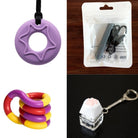 Product collage featuring items from the "2 Chew Necklaces + 2 Fidget Toys Bundle" with a purple star-shaped pendant on a black cord in the top left, a packaged black pendant with a cord in the top right, a tri-colored (red, yellow, and purple) coiled ring fidget toy in the bottom left, and a white paw keycap keychain for keyboard enthusiasts in the bottom right.